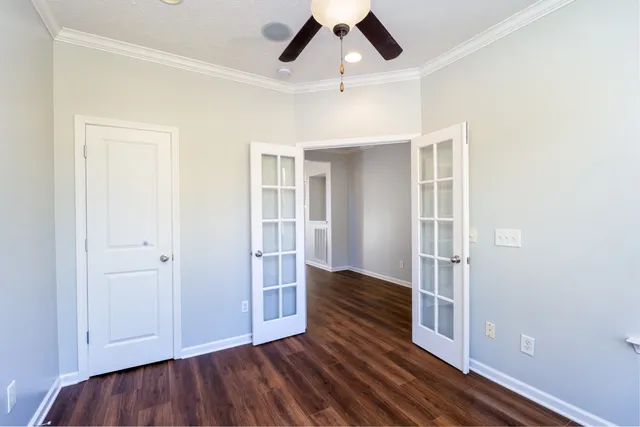 an empty room with wooden floor closet and windows