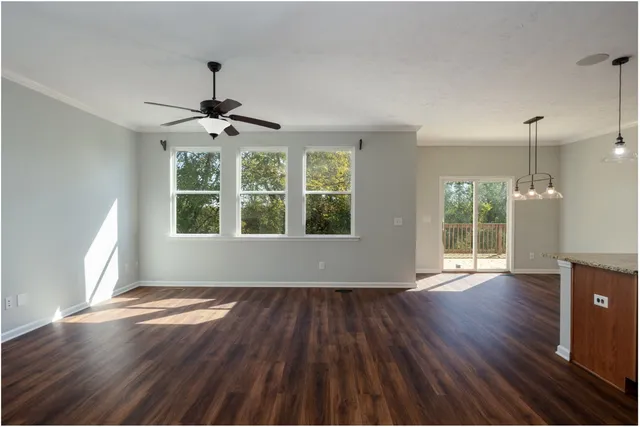 a view of an empty room with wooden floor fridge and a window