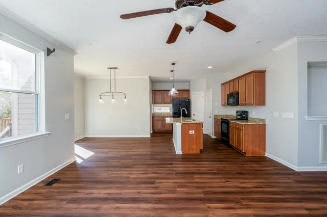a view of living room with kitchen island stainless steel appliances wooden floor and window