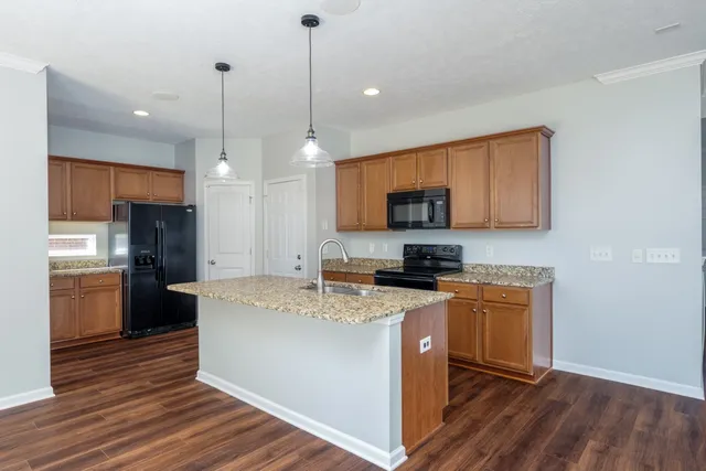 a kitchen with stainless steel appliances granite countertop a sink a stove a refrigerator cabinets and wooden floor