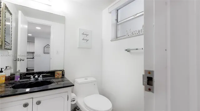 a bathroom with a granite countertop sink a toilet and a mirror