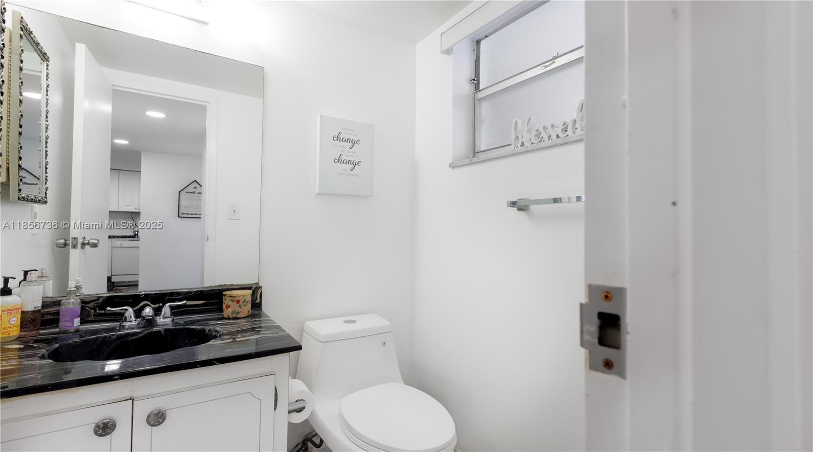 8321 Sands Point Boulevard, Unit D205 Tamarac, FL 33321 - Photo 9 of 18 a bathroom with a granite countertop sink a toilet and a mirror