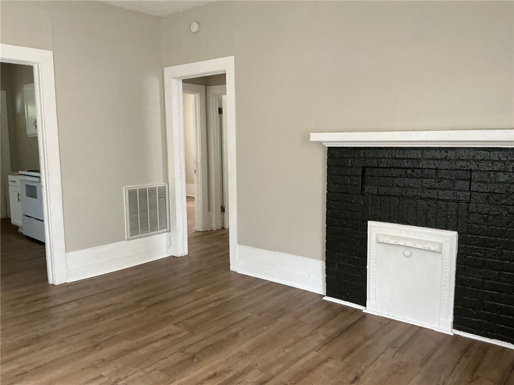 504 Caughlin Avenue Anderson, SC 29624 - Photo 2 of 15 An inviting room features warm wood flooring and a classic brick fireplace.