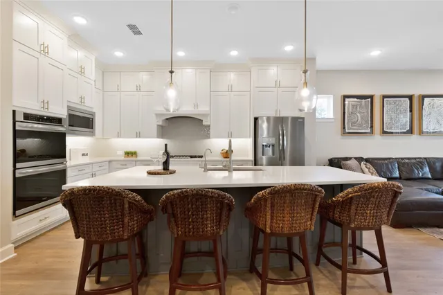 a kitchen with stainless steel appliances kitchen island granite countertop a table chairs sink and microwave