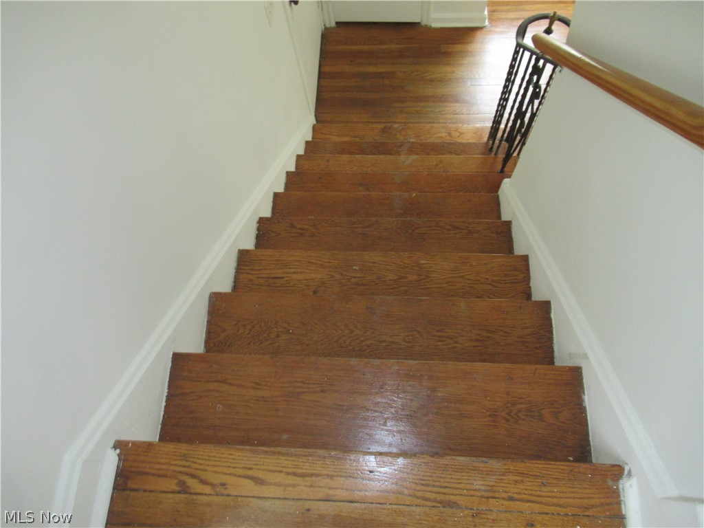 3824 East Antisdale Road Cleveland, OH 44118 - Photo 22 of 27 Staircase featuring wood-finish treads, a wood handrail, and white wall paneling with decorative trim