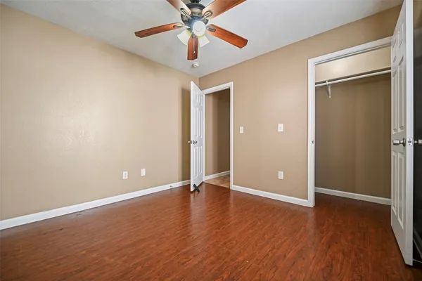 an empty room with wooden floor closet and fan chandelier fan
