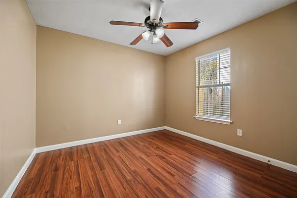 a view of a room with wooden floor a ceiling fan and windows