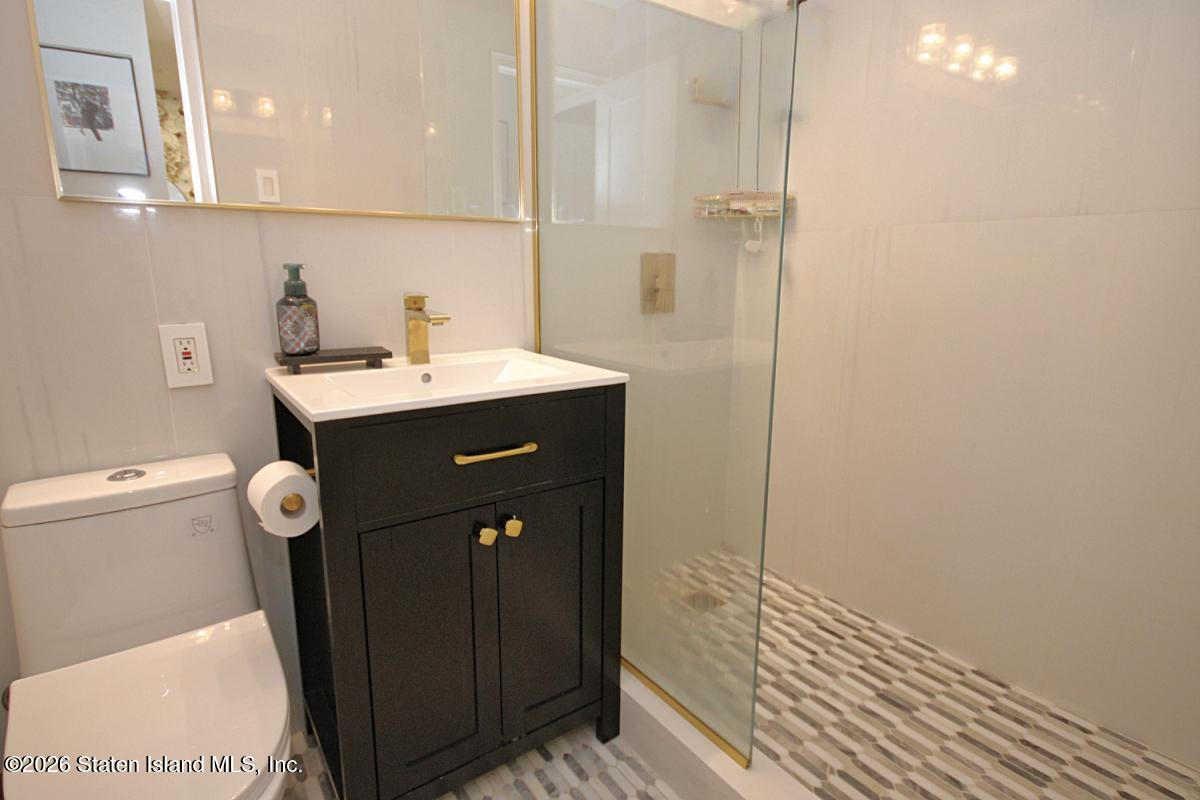 1000 Clove Road, Unit 2P Staten Island, NY 10301 - Photo 14 of 22 a bathroom with a sink a toilet a mirror and shower