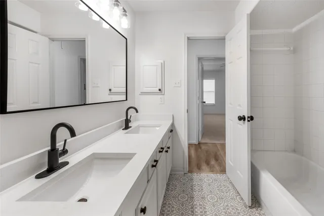 a bathroom with double vanity sink and a bathtub
