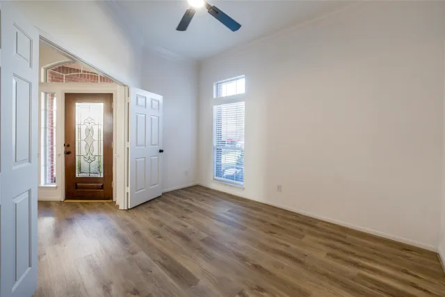 an empty room with wooden floor and windows