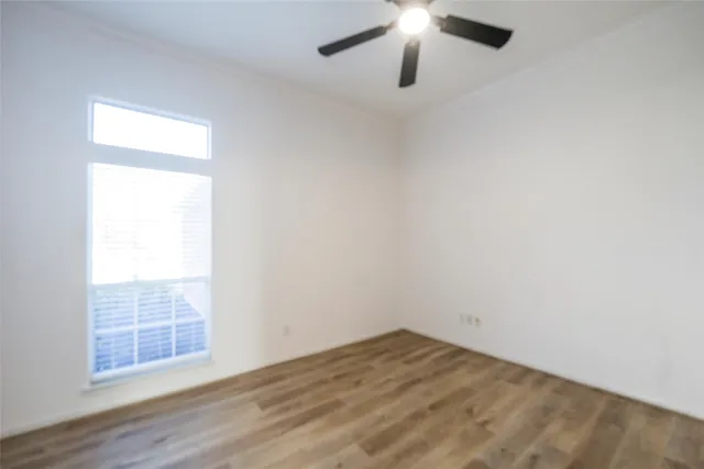 an empty room with wooden floor chandelier fan and windows