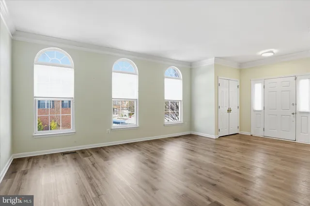 a view of an empty room with wooden floor and stairs