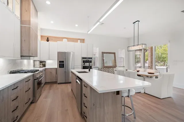 a large kitchen with kitchen island a island a stove a sink a dining table and chairs