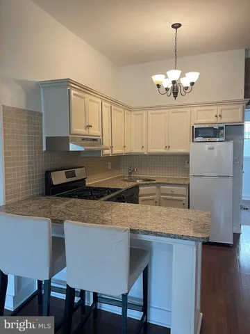 a kitchen with stainless steel appliances granite countertop a sink dishwasher a stove refrigerator and microwave with wooden floor