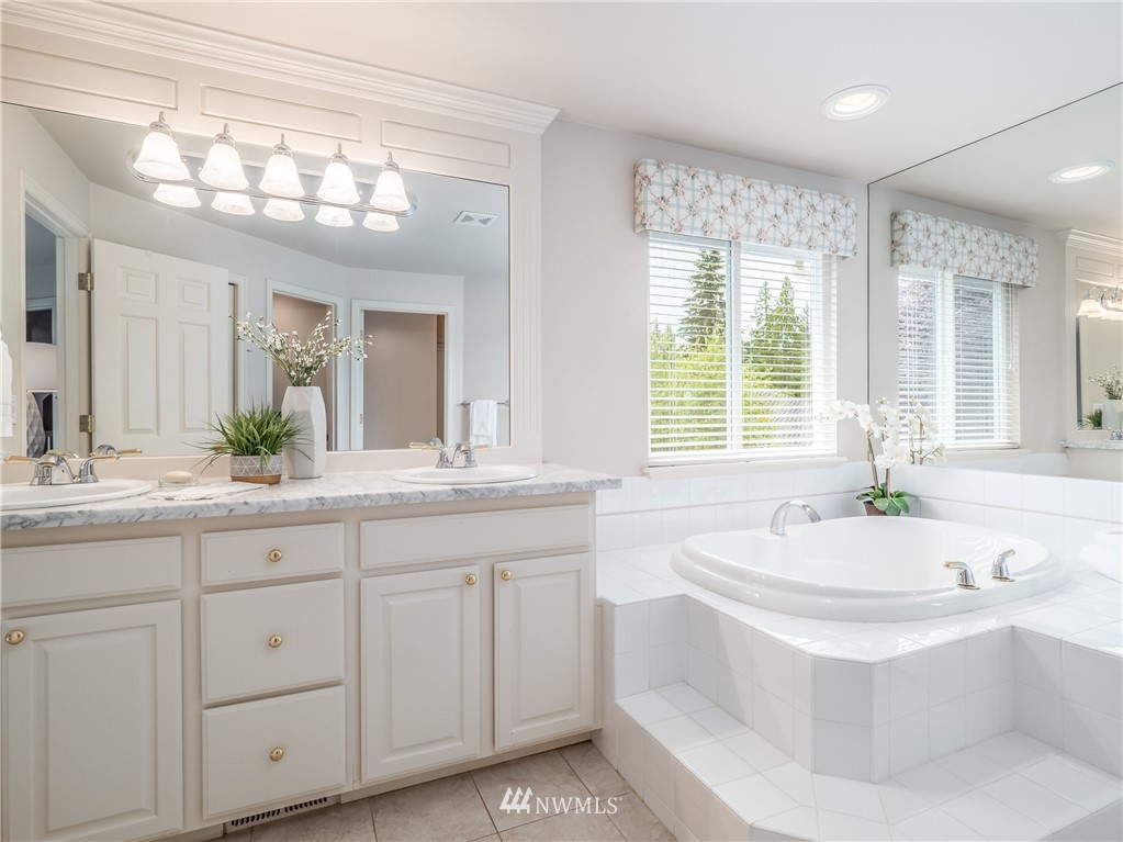 20104 27th Avenue Southeast Bothell, WA 98012 - Photo 16 of 27 a spacious bathroom with a granite countertop sink a large mirror a bathtub and next to a window