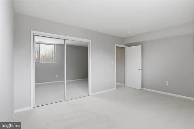 a view of an empty room with closet and a window