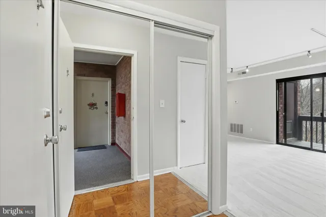 a view of a hallway with wooden floor and closet