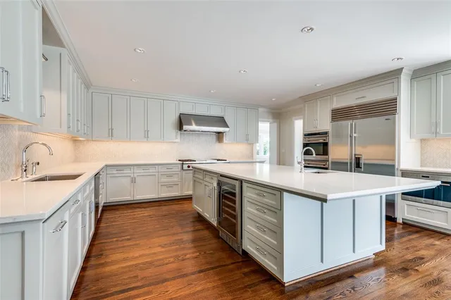 a kitchen with a sink stove cabinets and wooden floor