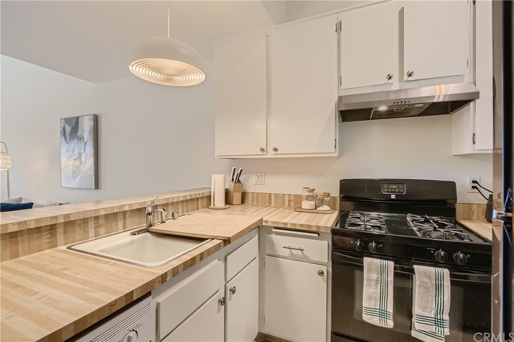 207 Orange Blossom, Unit 23 Irvine, CA 92618 - Photo 6 of 28 a kitchen with granite countertop a sink a stove and cabinets