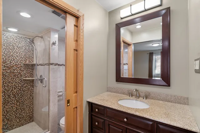 a bathroom with a granite countertop sink mirror and shower
