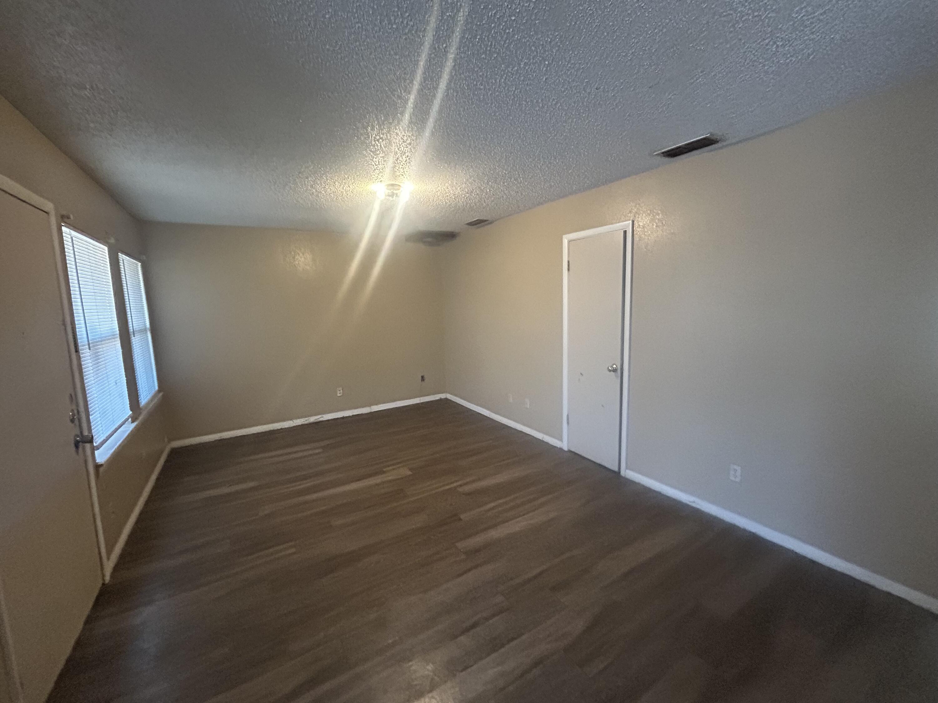 100 Pecos Place Plainview, TX 79072 - Photo 12 of 32 an empty room with wooden floor and windows