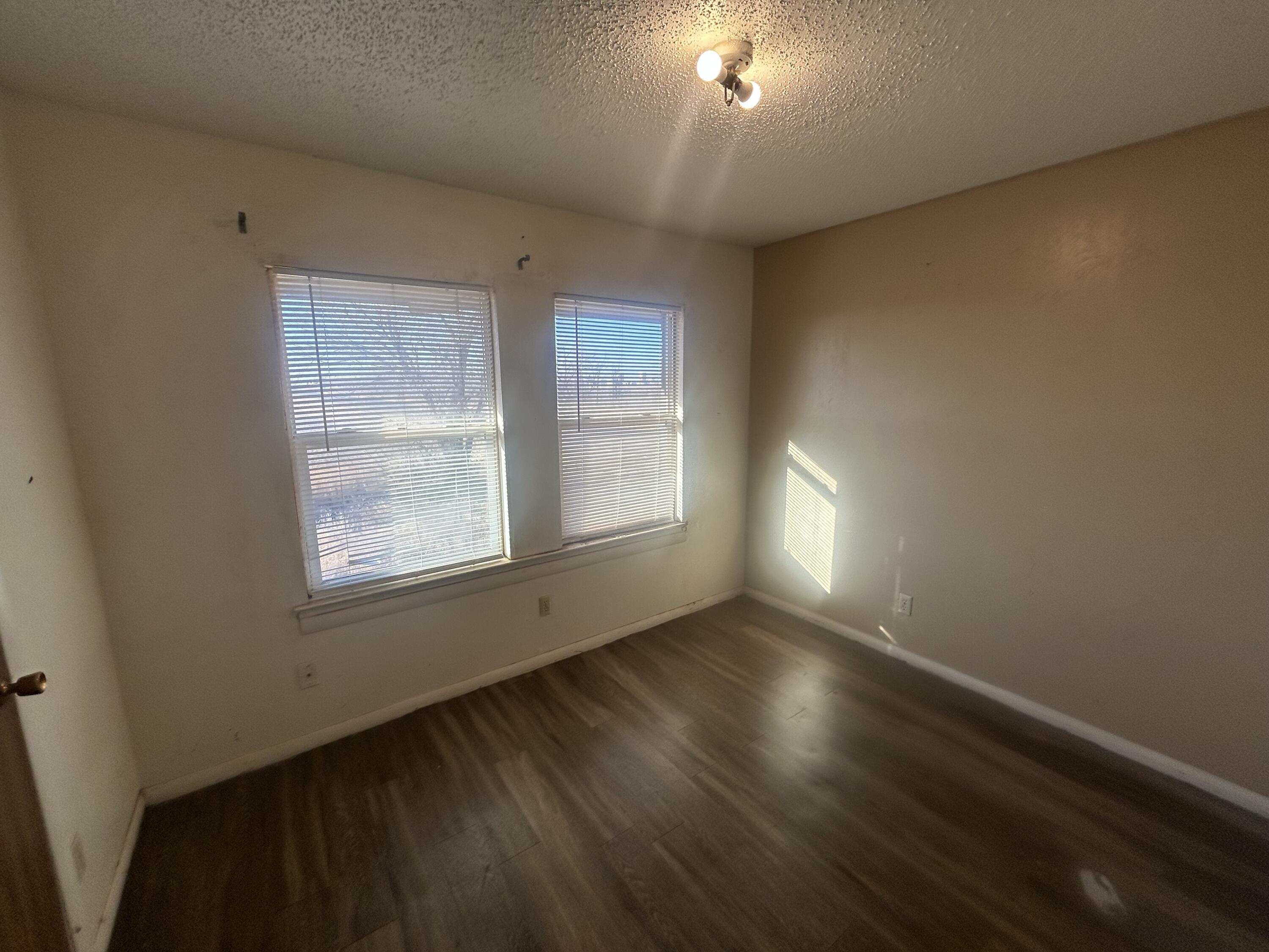 100 Pecos Place Plainview, TX 79072 - Photo 16 of 32 an empty room with wooden floor and windows