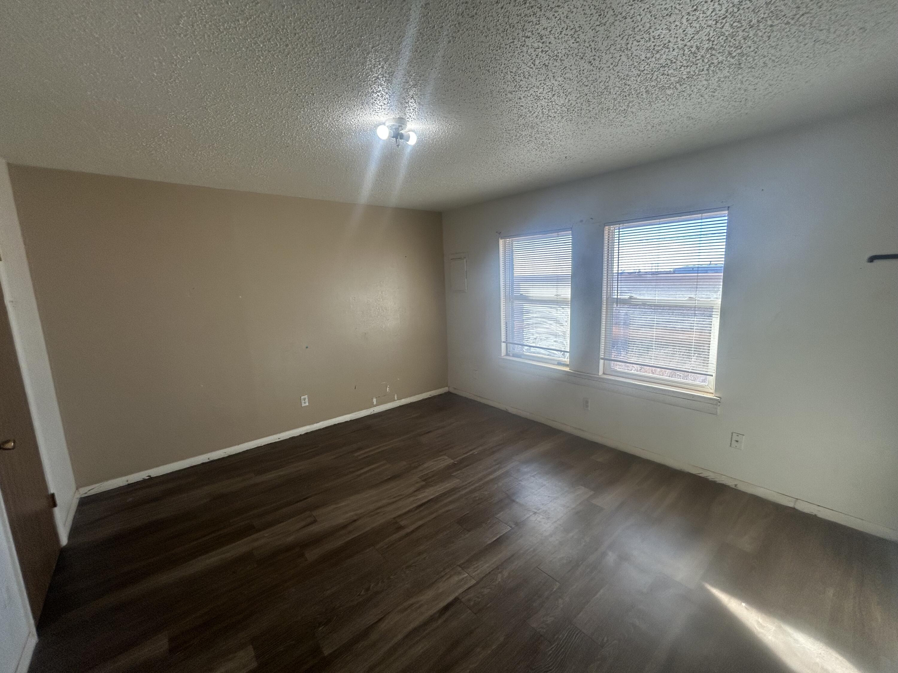 100 Pecos Place Plainview, TX 79072 - Photo 17 of 32 an empty room with wooden floor and windows