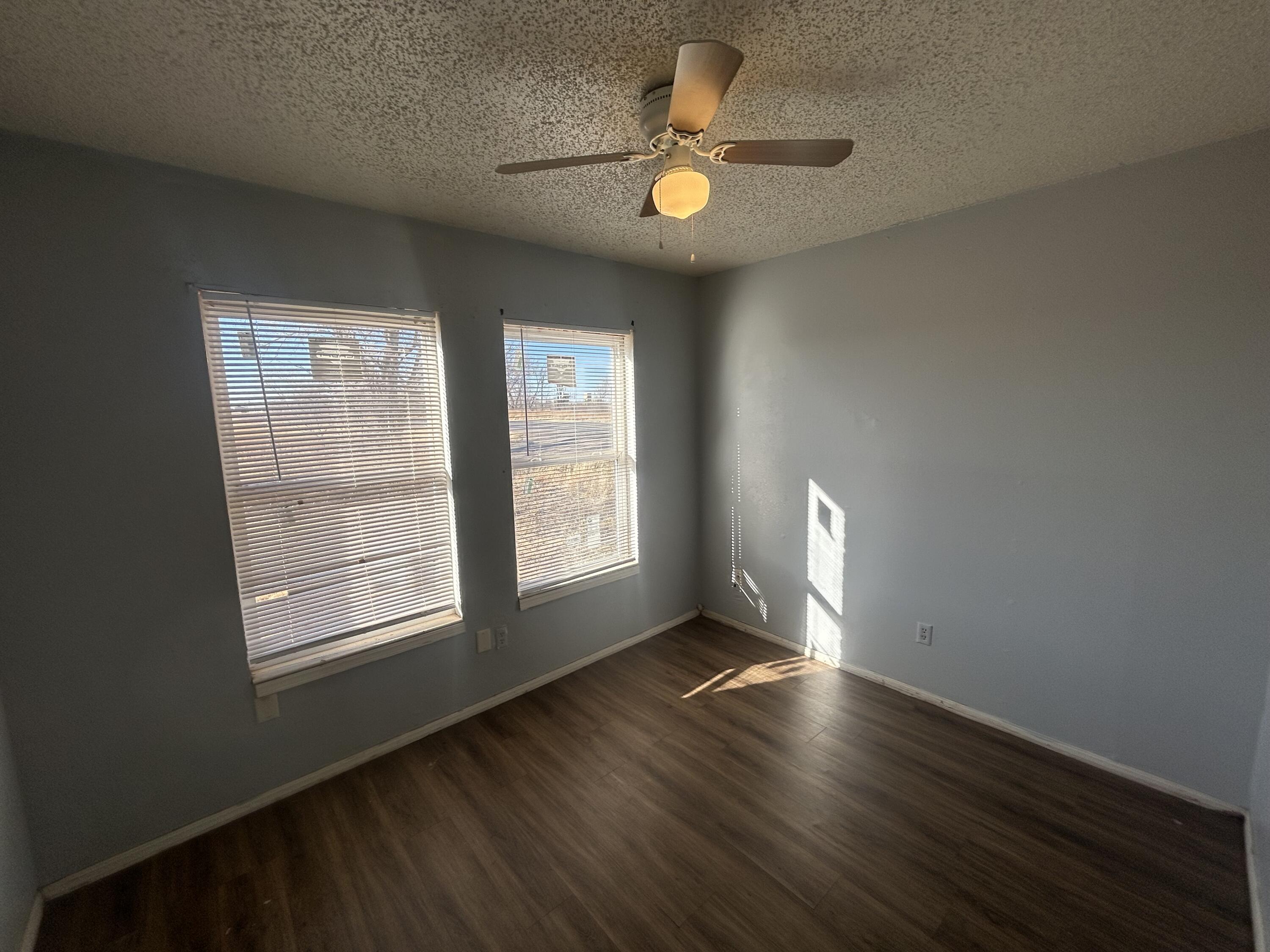 100 Pecos Place Plainview, TX 79072 - Photo 10 of 32 an empty room with wooden floor and windows
