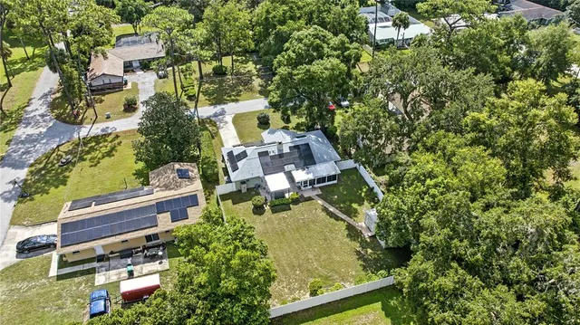 an aerial view of residential house with outdoor space and trees all around
