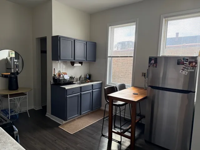 a kitchen with stainless steel appliances granite countertop a refrigerator a sink dishwasher a stove a dining table and chairs with wooden floor