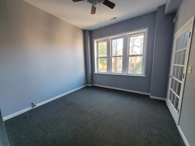 an empty room with a window and a ceiling fan