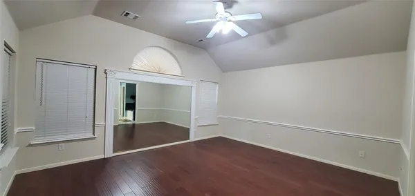 an empty room with wooden floor and windows