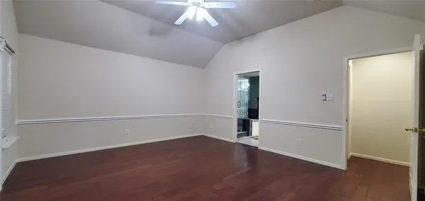 an empty room with wooden floor chandelier and windows