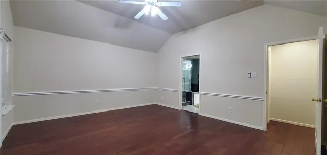 an empty room with wooden floor chandelier and windows