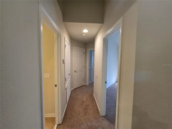 an empty room with a chandelier fan and windows
