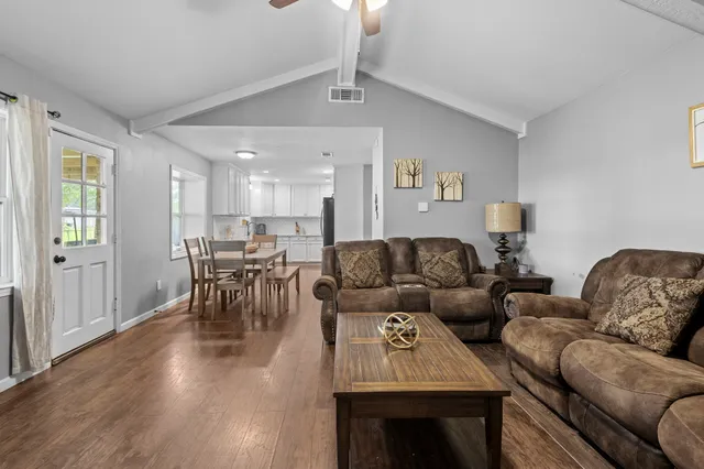 a living room with furniture kitchen view and a wooden floor