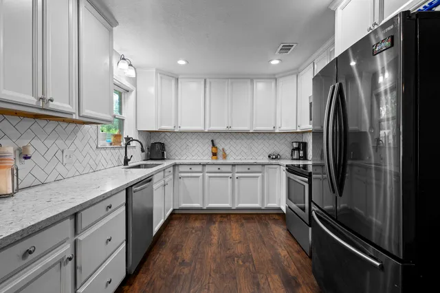 a kitchen with a refrigerator sink and white cabinets