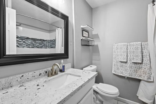 a bathroom with a granite countertop toilet sink and mirror