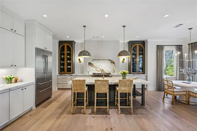 a kitchen with stainless steel appliances kitchen island granite countertop a table chairs stove and cabinets