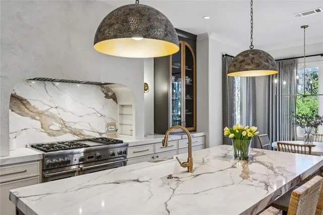 a kitchen with stainless steel appliances kitchen island granite countertop a table and a chandelier