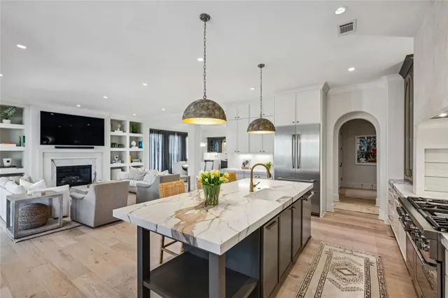 a open kitchen with stainless steel appliances granite countertop a stove top oven a sink dishwasher a dining table and chairs with wooden floor