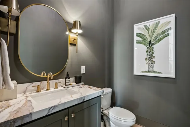 a bathroom with a granite countertop sink mirror vanity and toilet