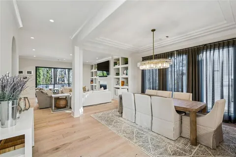 a living room with furniture a fireplace and a dining table with wooden floor
