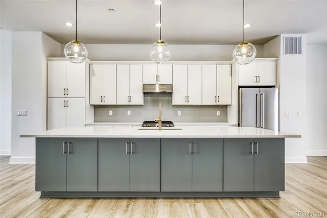 a kitchen with kitchen island granite countertop a sink cabinets and wooden floor