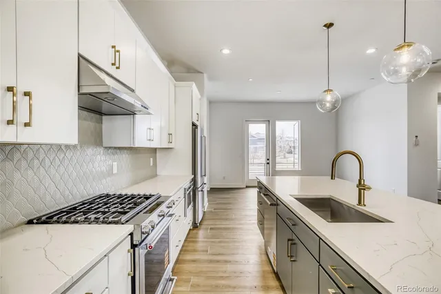 a kitchen with stainless steel appliances a sink a stove a chimney a sink and cabinets