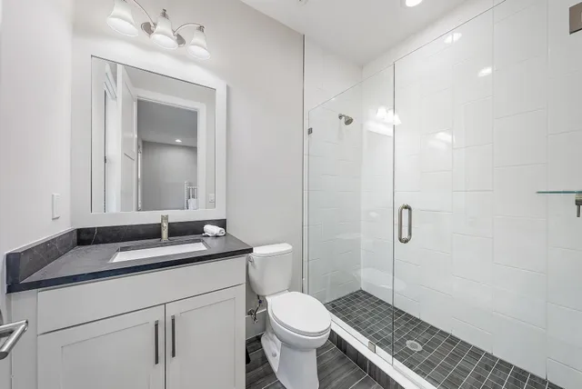 a bathroom with a granite countertop sink toilet and shower