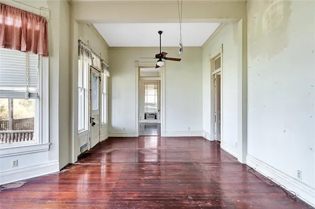 an empty room with wooden floor and windows