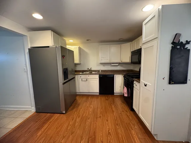 a kitchen with stainless steel appliances a refrigerator a sink dishwasher a stove and white cabinets with wooden floor