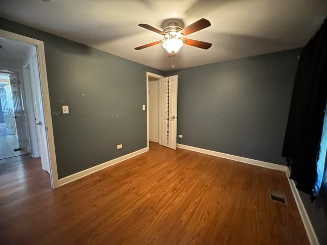 an empty room with wooden floor and a ceiling fan