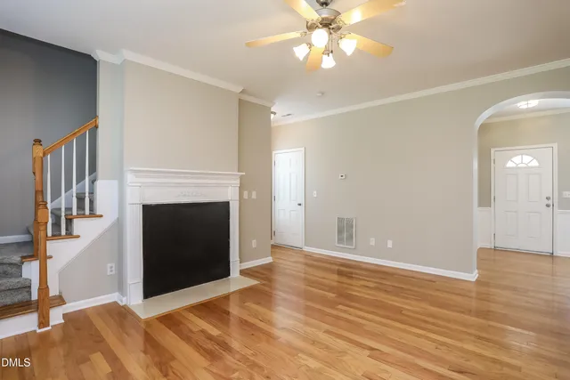 a view of an empty room with wooden floor and a fireplace